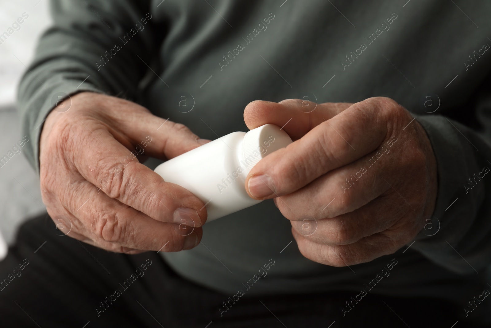 Photo of Senior man holding bottle with pills in his hands, closeup