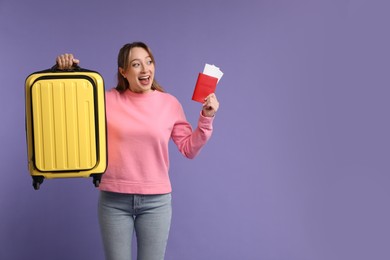 Emotional young woman with passport, ticket and suitcase on purple background, space for text