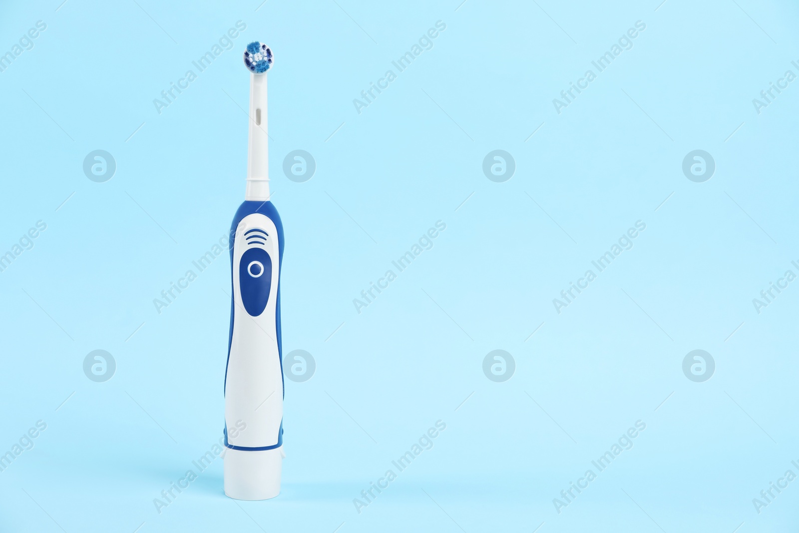 Photo of Electric toothbrush on light blue background, space for text