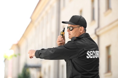 Male security guard using portable radio transmitter outdoors