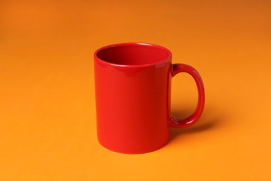 Photo of One red ceramic mug on orange background
