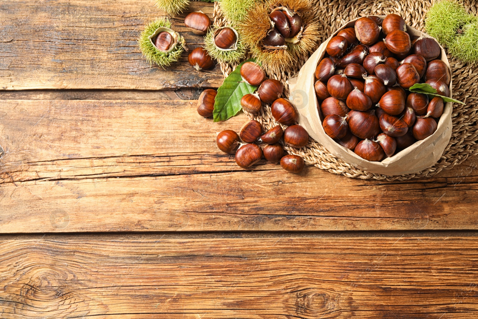 Photo of Fresh sweet edible chestnuts on wooden table, flat lay. Space for text