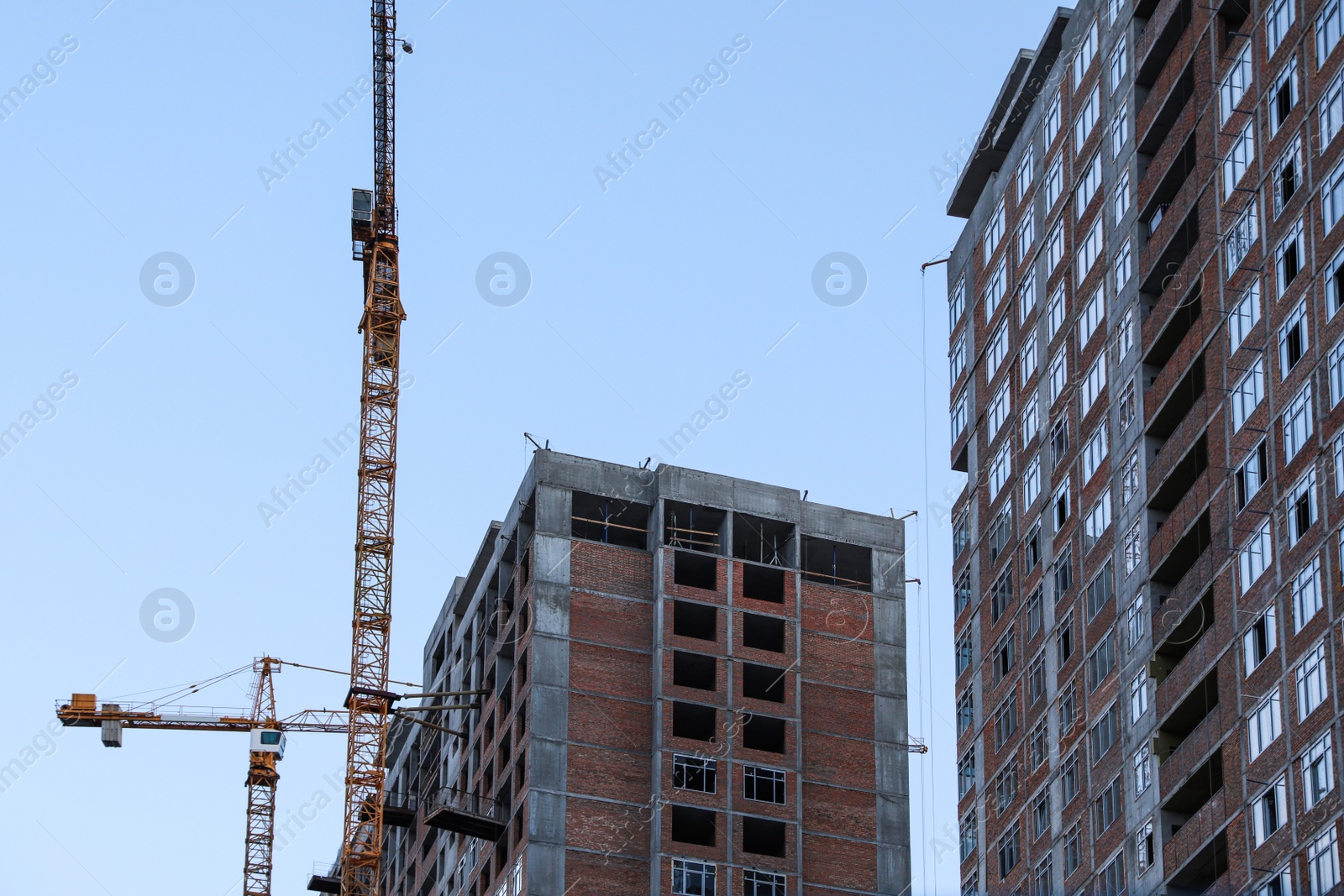 Photo of Construction crane and unfinished building against blue sky