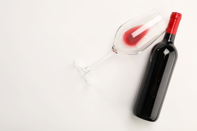Photo of Bottle of expensive red wine and wineglass on white background, top view. Space for text