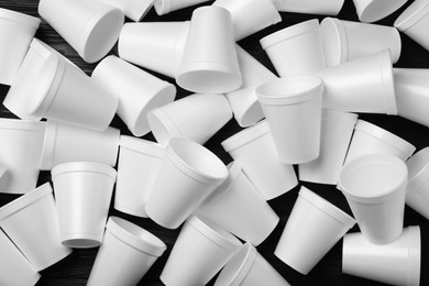 Many white styrofoam cups on black wooden table, flat lay
