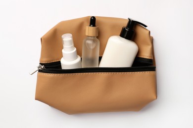 Photo of Preparation for spa. Compact toiletry bag with cosmetic products on white background, top view