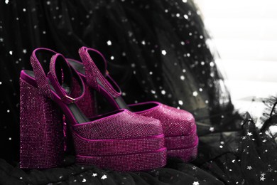 Photo of New pink high heeled shoes with platform and square toes on black cloth indoors