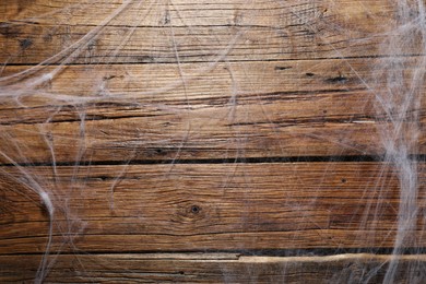 Creepy white cobweb hanging on wooden wall