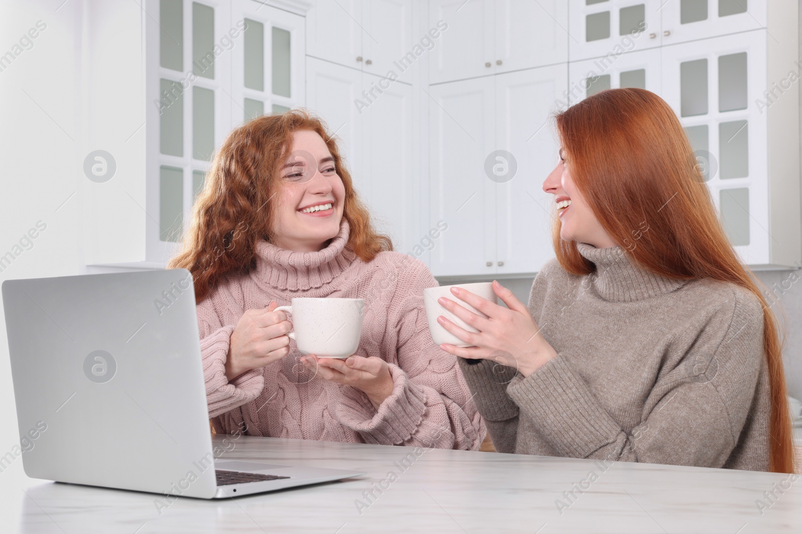 Photo of Beautiful young sisters spending time together in kitchen