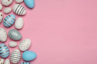 Photo of Flat lay composition with festively decorated Easter eggs on pink wooden table. Space for text