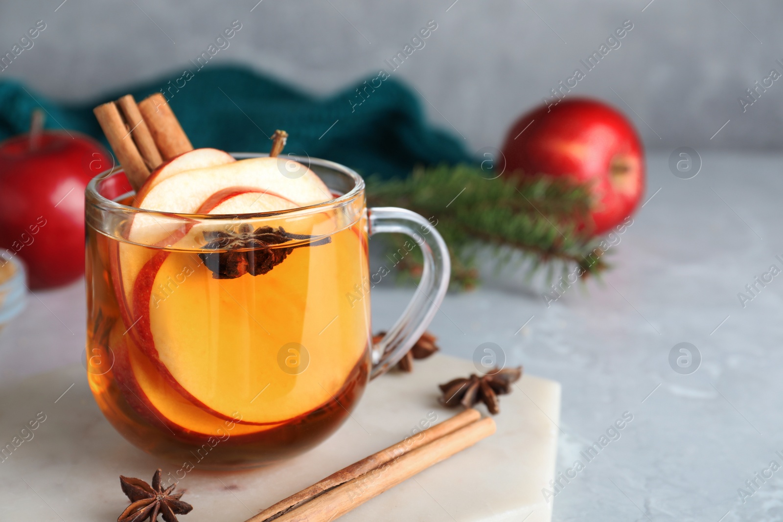 Photo of Aromatic hot mulled cider on light grey marble table. Space for text