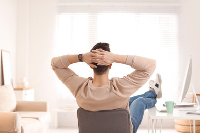 Young man relaxing at table in office during break