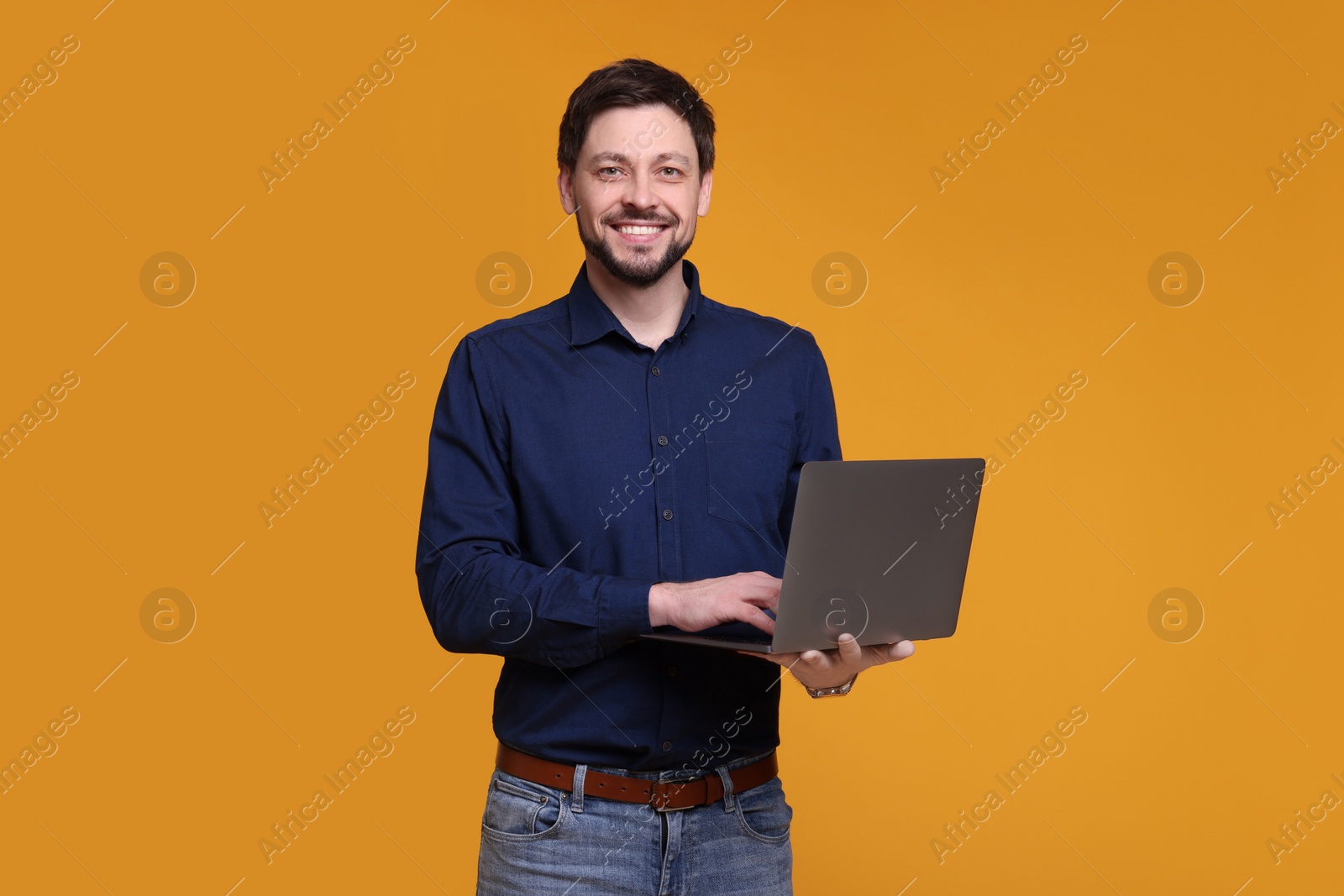 Photo of Happy man with laptop on yellow background