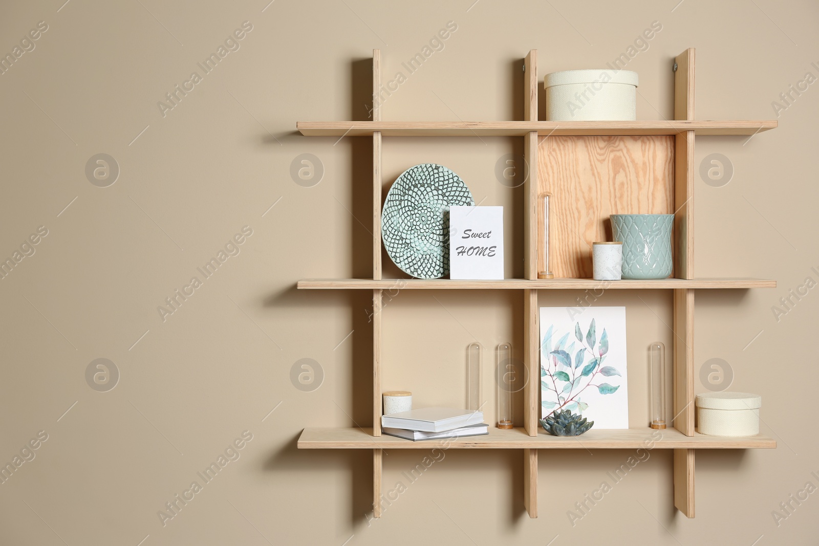 Photo of Wooden shelves with different decorative elements on beige wall, space for text