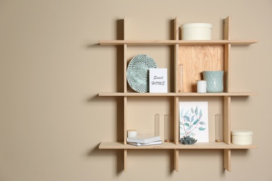 Photo of Wooden shelves with different decorative elements on beige wall, space for text