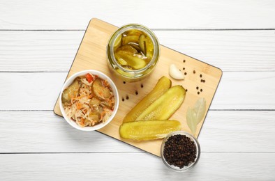 Tasty pickled cucumbers and spices on white wooden table, flat lay