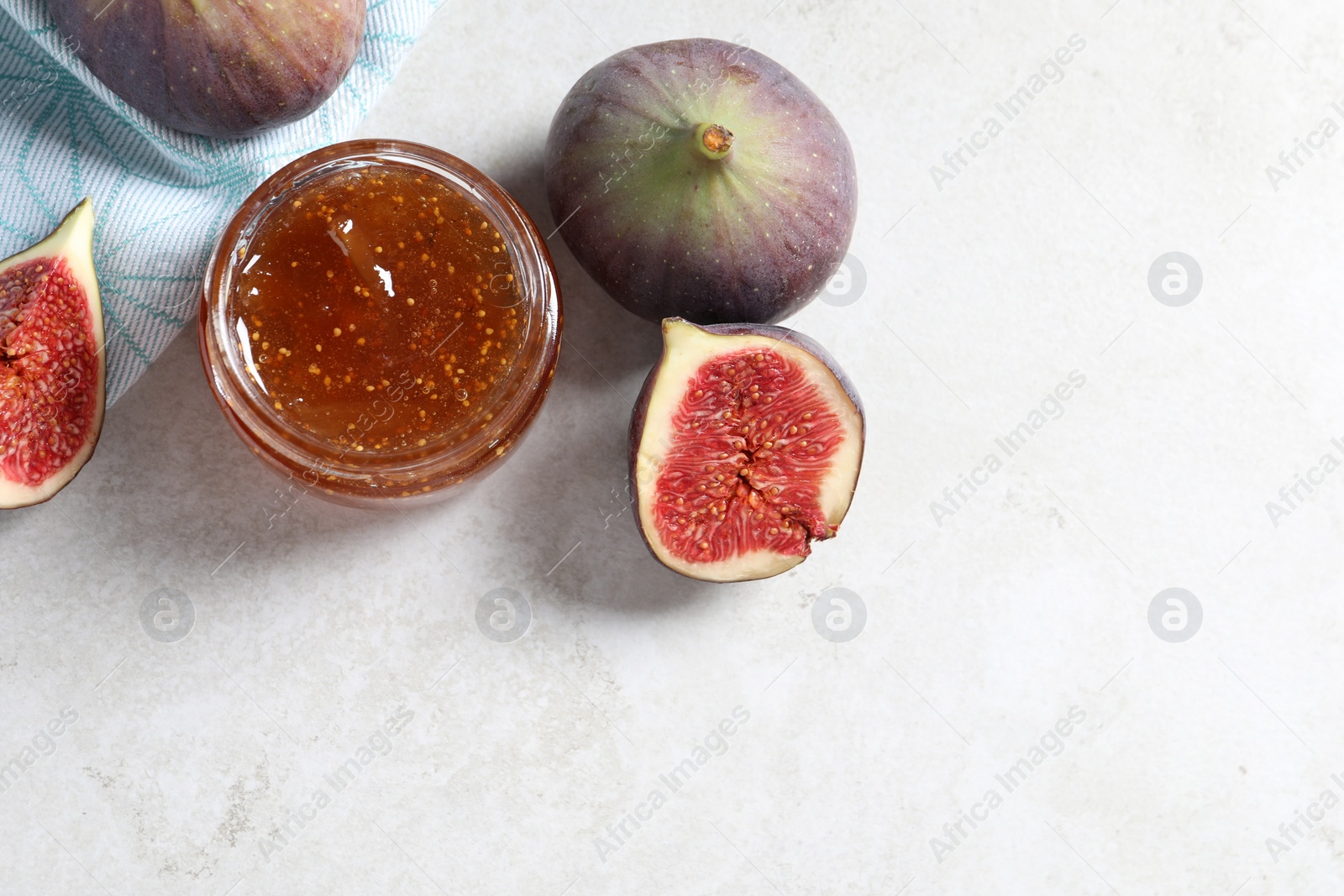 Photo of Jar of tasty sweet jam and fresh figs on light table, flat lay. Space for text