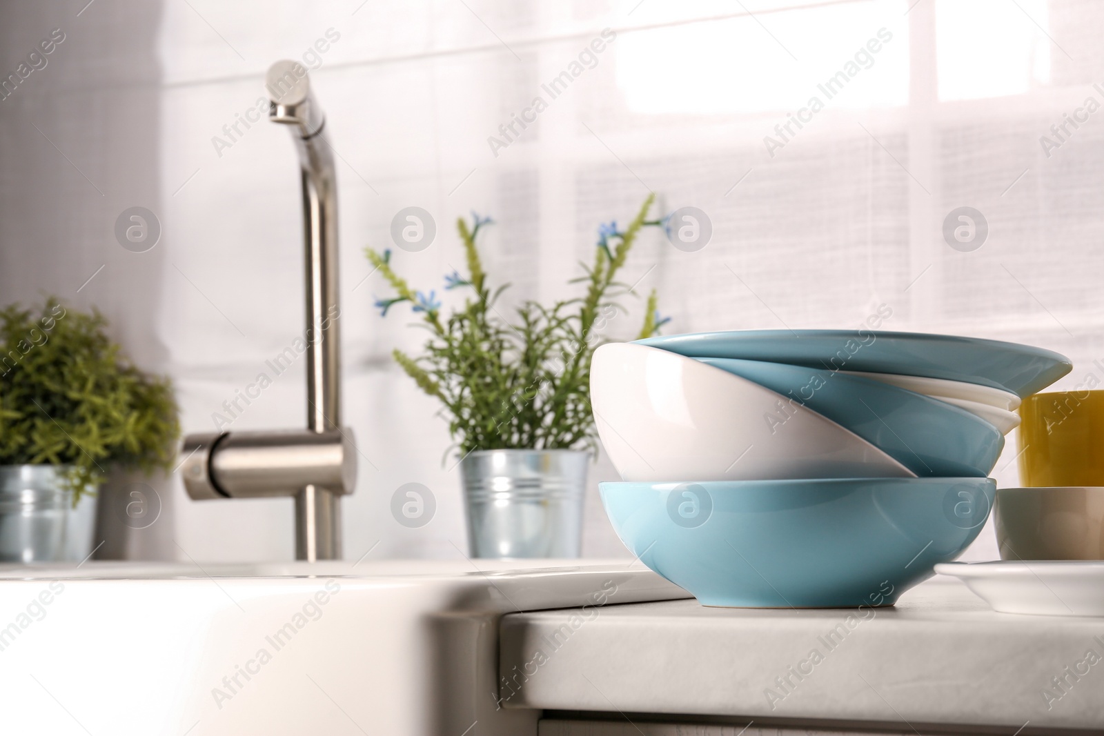 Photo of Clean tableware on light countertop in kitchen, space for text