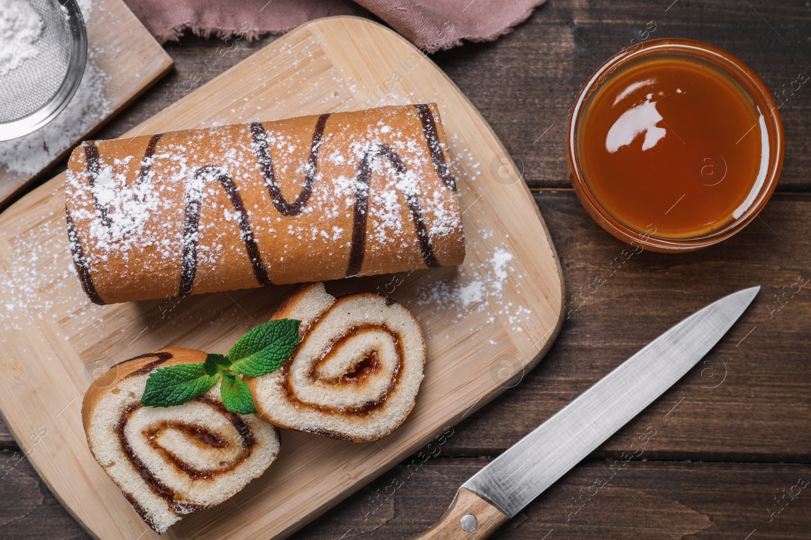 Photo of Tasty cake roll with jam on wooden table, flat lay