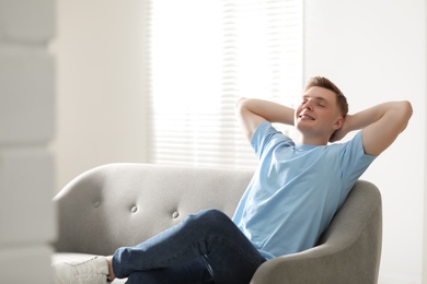 Photo of Teenage boy sitting on sofa at home. Space for text