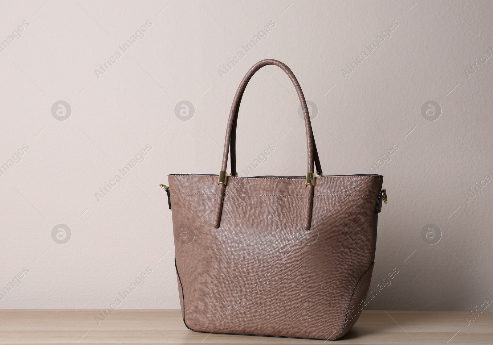 Photo of Stylish leather woman's bag on wooden table