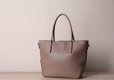 Photo of Stylish leather woman's bag on wooden table