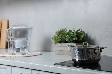 Photo of Potted artificial plant and pot on white countertop in kitchen