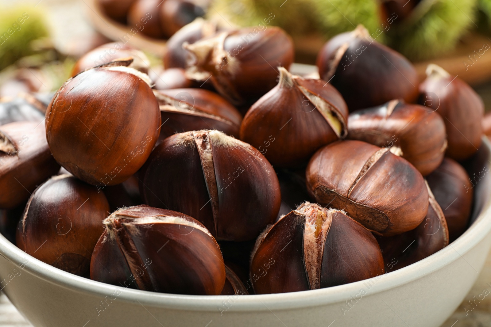 Photo of Delicious roasted edible chestnuts in bowl, closeup