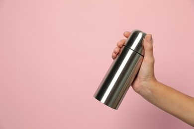 Photo of Woman holding modern thermos on pink background, closeup. Space for text