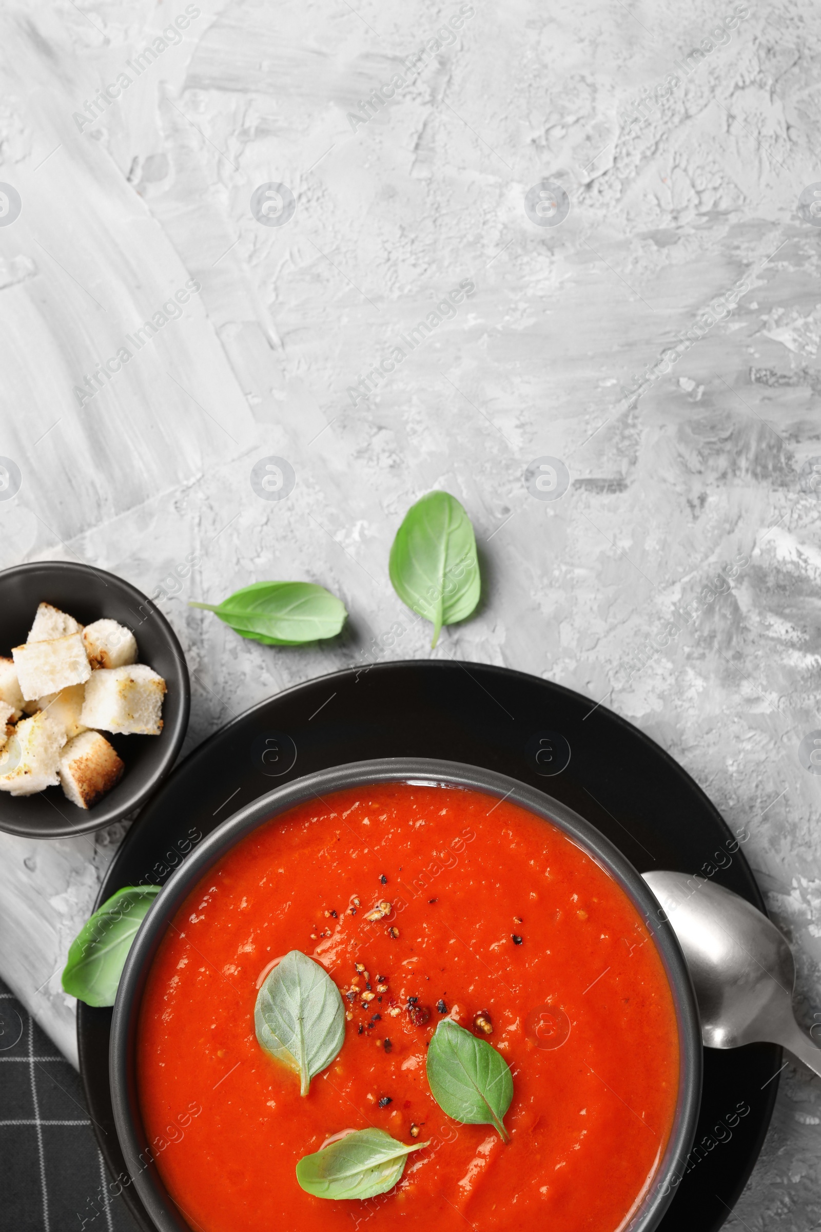 Photo of Delicious tomato cream soup served on grey textured table, flat lay. Space for text