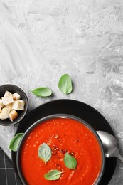 Photo of Delicious tomato cream soup served on grey textured table, flat lay. Space for text