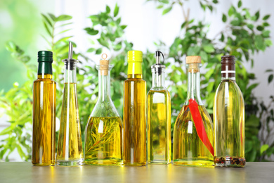 Photo of Different sorts of cooking oil in bottles on light grey table