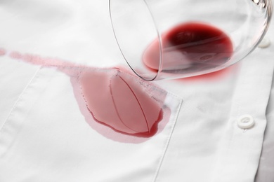 Photo of Overturned glass and spilled exquisite red wine on white shirt. Space for text