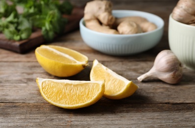 Photo of Cut lemon and garlic on wooden table. Cough remedies