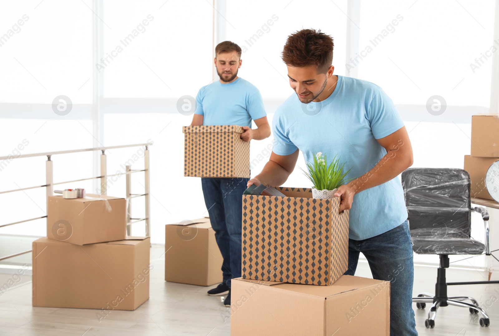 Photo of Professional worker with cardboard box and his colleague in office. Moving service