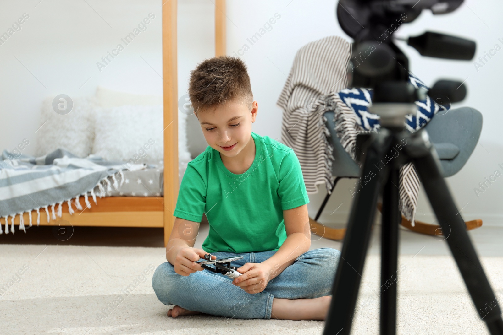 Photo of Cute little blogger with phone and selfie stick recording video at home