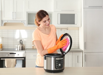Photo of Woman cleaning modern multi cooker at table in kitchen