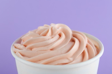 Cup with tasty frozen yogurt on violet background, closeup