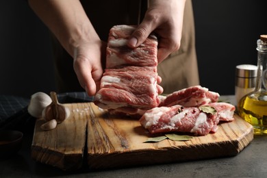 Photo of Man holding raw ribs at grey table, closeup