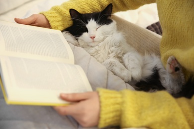 Woman with cute cat reading book, closeup