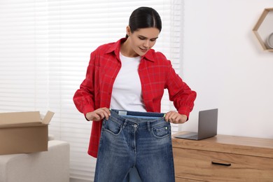 Photo of Young woman with just unpacked new jeans at home. Online shopping