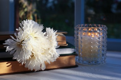 Photo of Book with beautiful chrysanthemum flowers as bookmark and candle on white table
