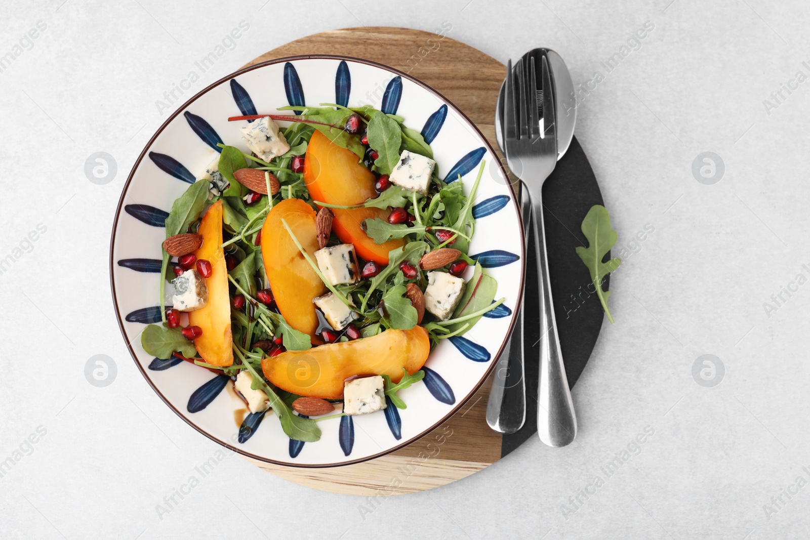 Photo of Tasty salad with persimmon, blue cheese, pomegranate and almonds served on white table, top view