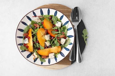 Tasty salad with persimmon, blue cheese, pomegranate and almonds served on white table, top view