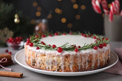 Traditional Christmas cake decorated with rosemary and cranberries on table, closeup