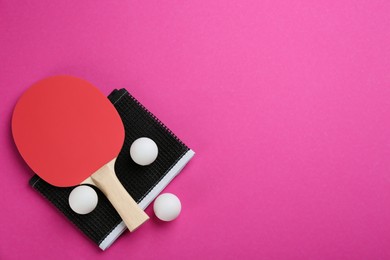 Ping pong racket, net and balls on pink background, flat lay. Space for text