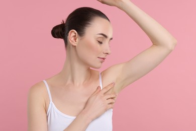 Beautiful woman showing armpit with smooth clean skin on pink background