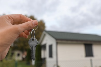 Real estate agent holding keys to new house outdoors, closeup. Space for text