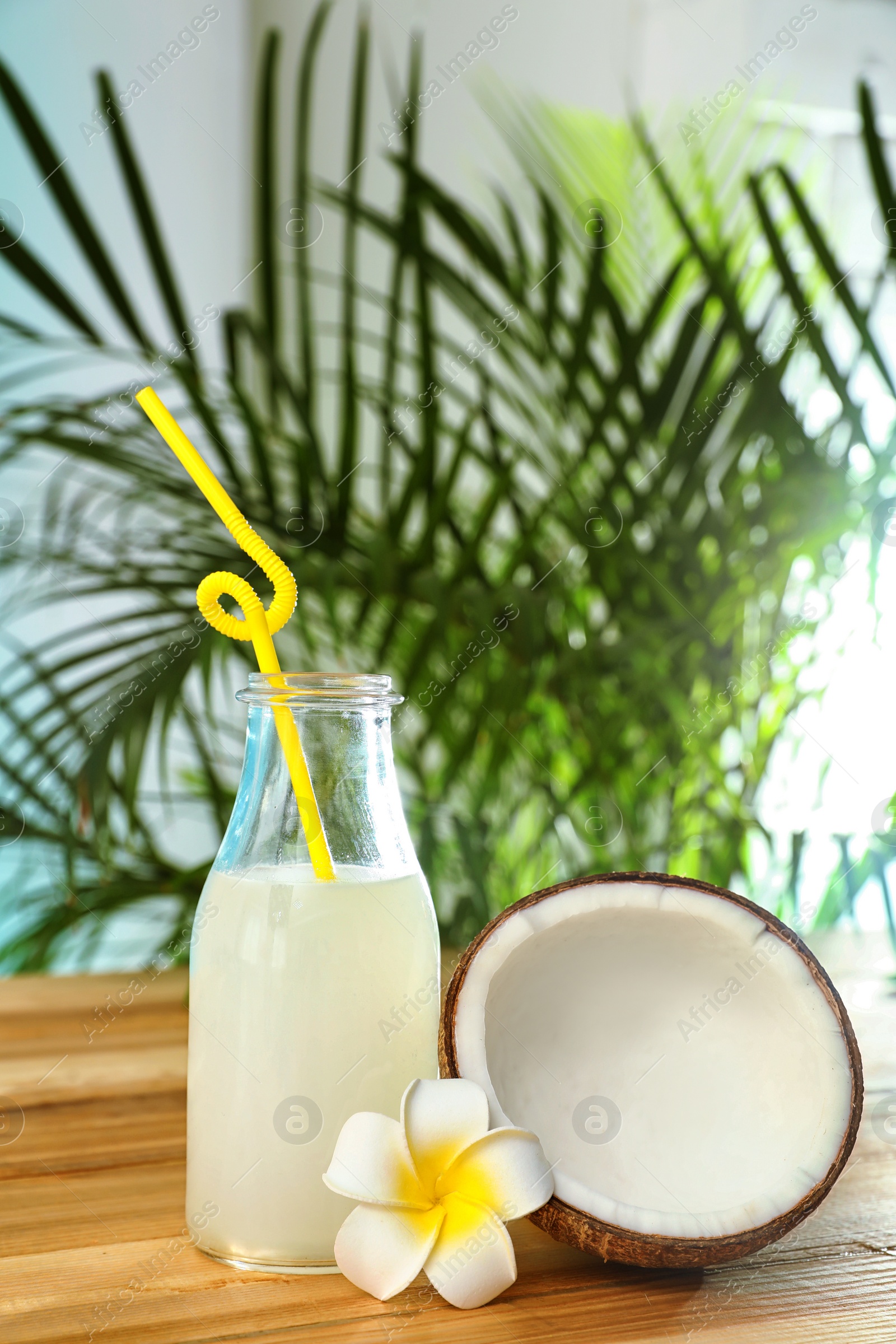 Photo of Composition with bottle of coconut water on wooden table against blurred background