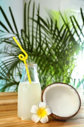 Photo of Composition with bottle of coconut water on wooden table against blurred background